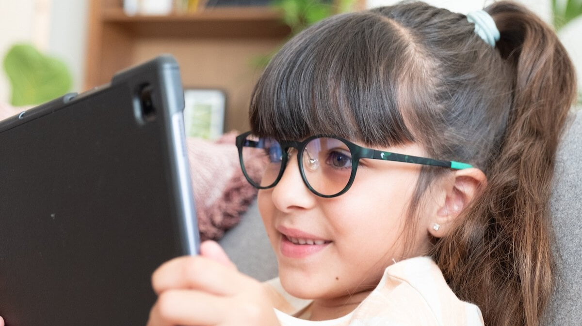 une petite fille portant des lunettes Horus X tout en regardant quelque chose sur sa tablette