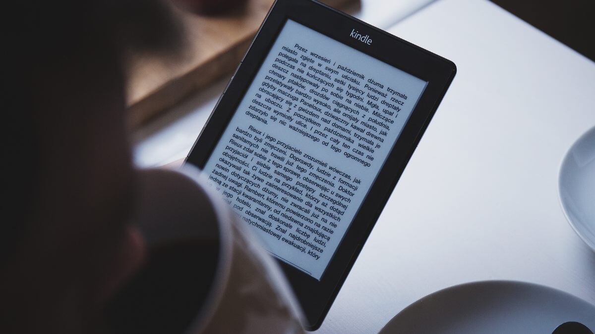 un homme utilisant un lecteur de livre électronique tout en buvant du café