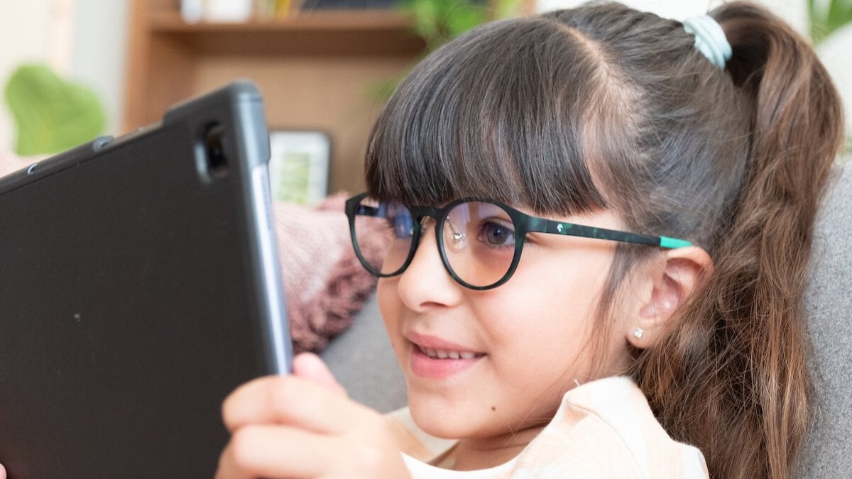 une petite fille portant des lunettes Horus X tout en regardant quelque chose sur sa tablette