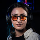 Notre modèle Hélène porte les lunettes gamer urban revolution avec verre ambré et un casque audio sur fond noir de face