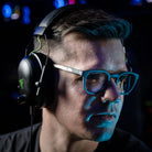 Notre cofondateur Matthieu porte les lunettes gamer urban revolution avec verre clair et un casque audio sur fond noir de profil